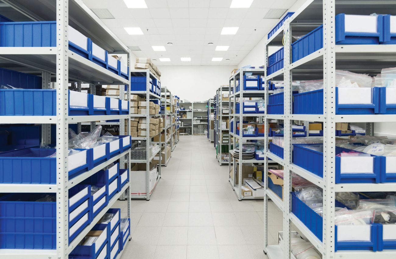 Industrial warehouse. White metal racks with blue plastic trays and cardboard boxes installed in them.