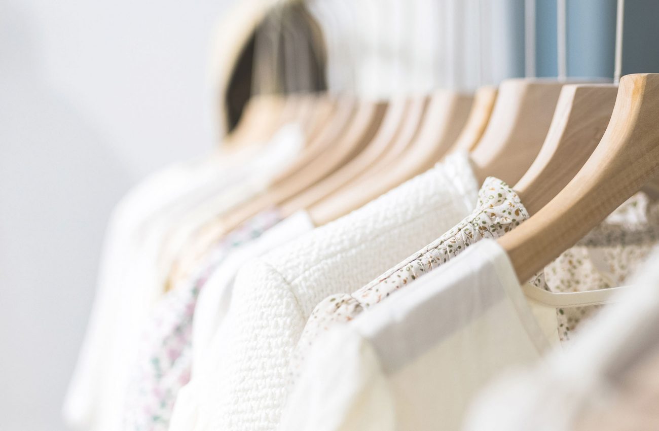 Row of different female clothes hanging on rack in hipster fashion show room in shopping mall. Trendy women wear