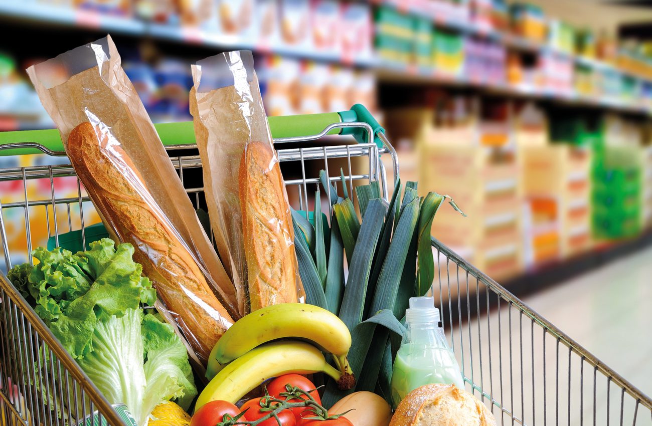 Shopping cart full of food in supermarket aisle elevated view